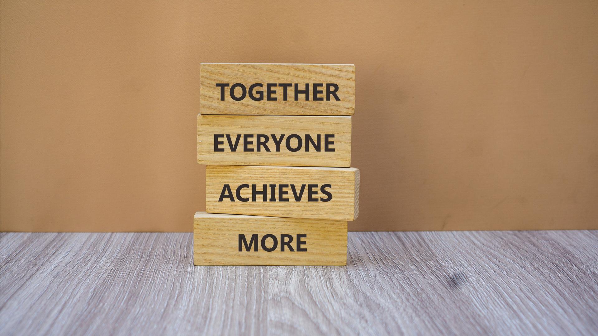 TOGETHER EVERYONE ACHIEVES MORE symbol. Copy space, text template. Concept word TOGETHER EVERYONE ACHIEVES MORE on wooden blocks with wood background. Business and financial concept.