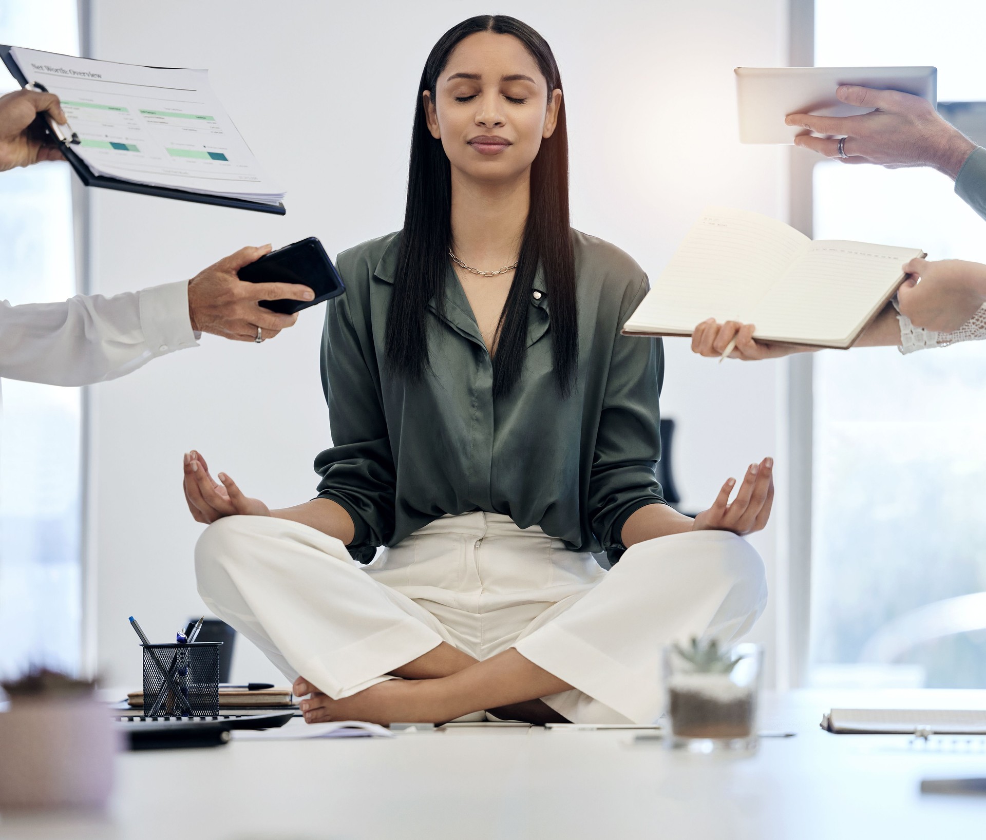 Shot of a young businesswoman meditating on a desk in a demanding work environment